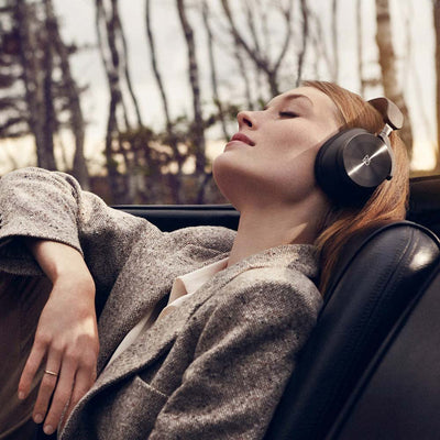 she relaxes in her car wearing h95 headphones by Bang & Olufsen